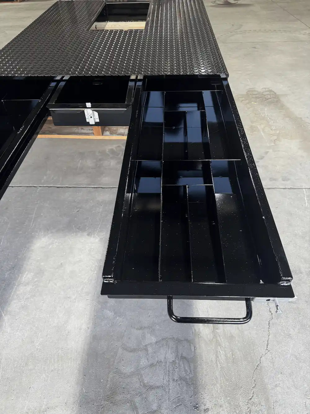 Black truck bed storage system with the right‑hand drawer extended.